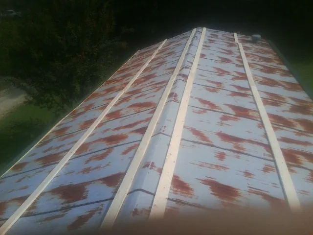 Rusted metal roof panels with new wood purlins before replacement — Storm Damage Roof Repair in East Moline by Roofing Brothers