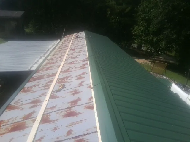 Old rusted panels beside newly installed green metal roofing — Wind Damage Roof Repair by Roofing Brothers in East Moline