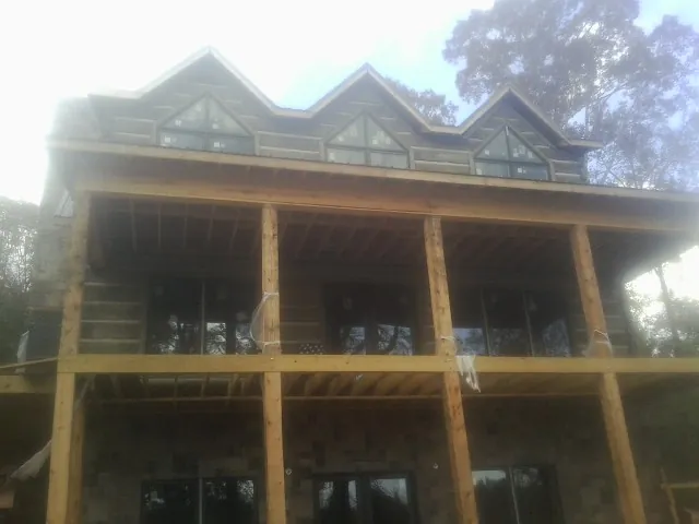 Dormers and porch framing on a large log home under construction — Roof Coating work by our crew in East Moline
