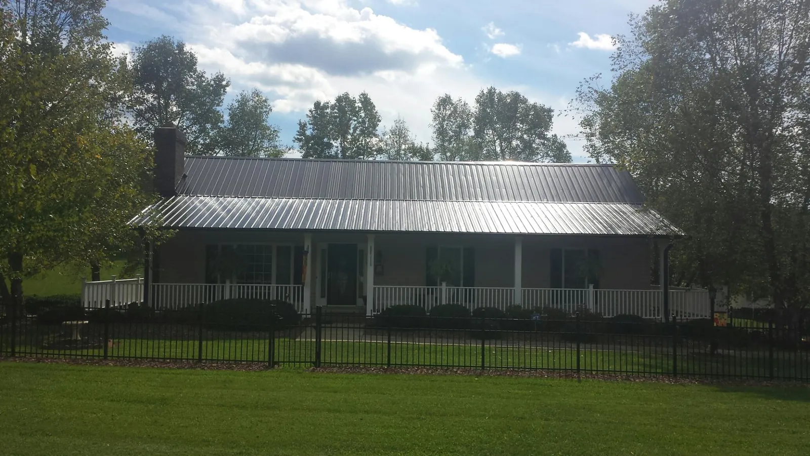 Gray metal roof on a brick ranch with a full width front porch — Gutter Guard Installation work by our crew in East Moline