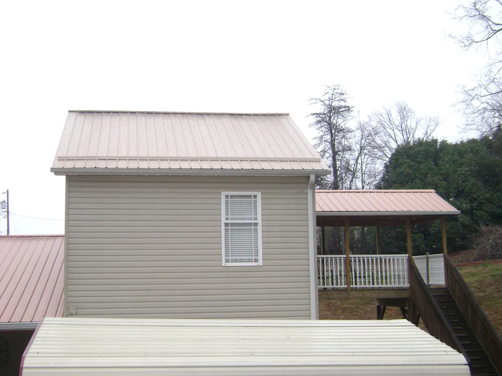 Tan metal roofs on a two story addition and attached porch, from a Roof Replacement job in East Moline