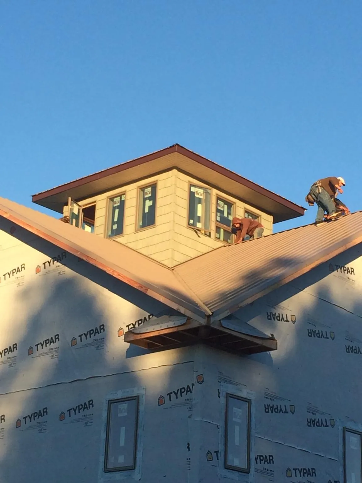 Roofers working around a rooftop cupola on a new metal roof at sunset — Roof Waterproofing in East Moline by Roofing Brothers